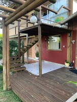 Um deck de madeira com uma escada que leva a uma área coberta com uma janela de vidro.
