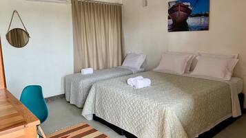 Habitación de hotel con dos camas, un escritorio, una silla, una cesta colgante y un cuadro en la pared.