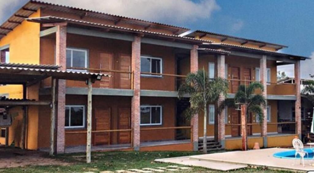 Un edificio de varios pisos con techo plano, balcones y una piscina.