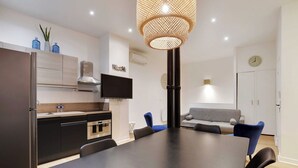 A modern kitchen with a dining area, including a large table and chairs, a TV, and a sofa. - Elegant Apartment - 2bd/6p - Hotel de Ville (Paris)