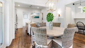 A dining area with a round table, wicker chairs, and a hanging light fixture. - Watercolor! Next to Dragonfly Pool, LSV, + 4 Bikes! Serene Location! (Santa Rosa Beach)