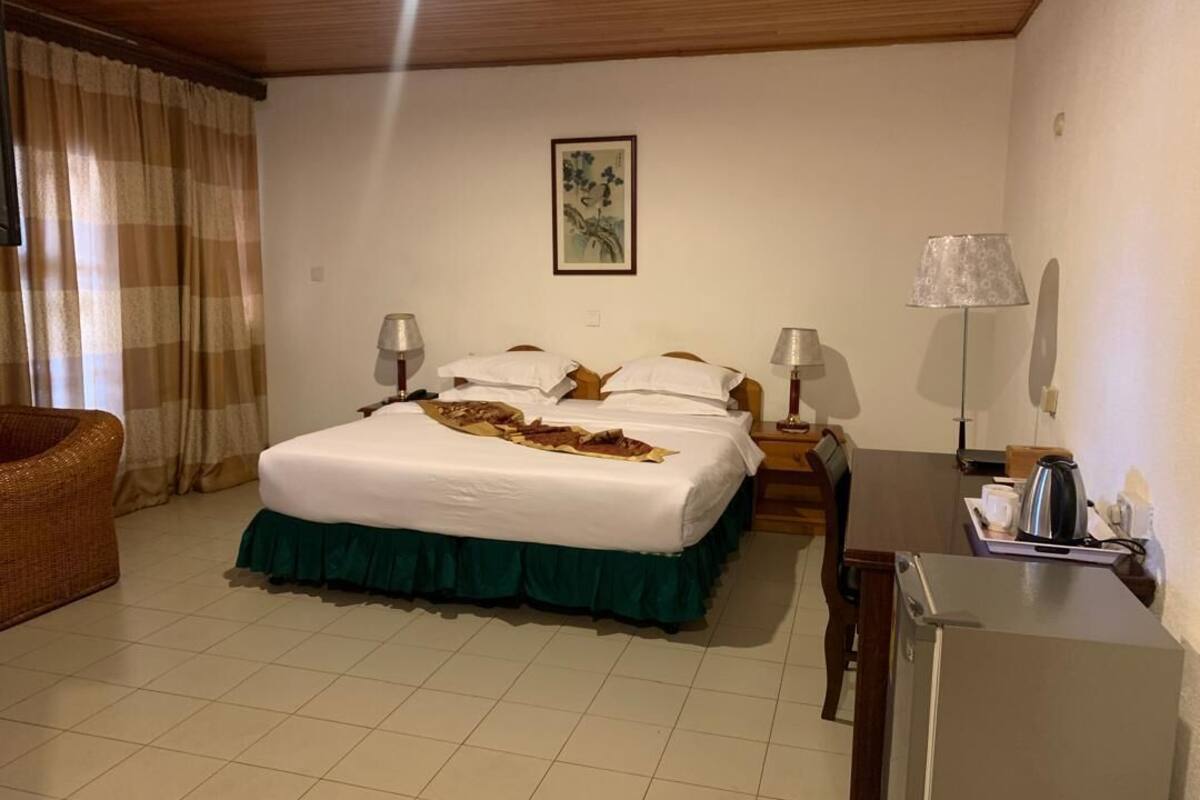 Een hotelkamer met een bed, twee nachtkastjes, een stoel, een bureau en een koelkast.