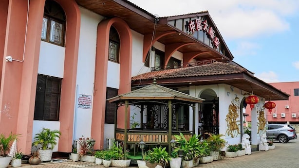A building with a traditional architectural style, featuring a covered entrance area with potted plants and a gazebo. - Royal Park Hotel (Kumasi)