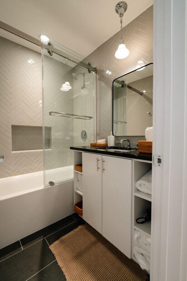 Une salle de bain moderne avec une douche à parois de verre, une baignoire et un meuble-lavabo avec un miroir.
