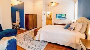 Een slaapkamer met een bed, een bureau, een stoel, een kledingkast en een televisie.