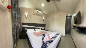 A hotel room with a bed, a flat-screen TV, a ceiling fan, and an air conditioning unit. - Sydney X cafe and Huts (Arambol)