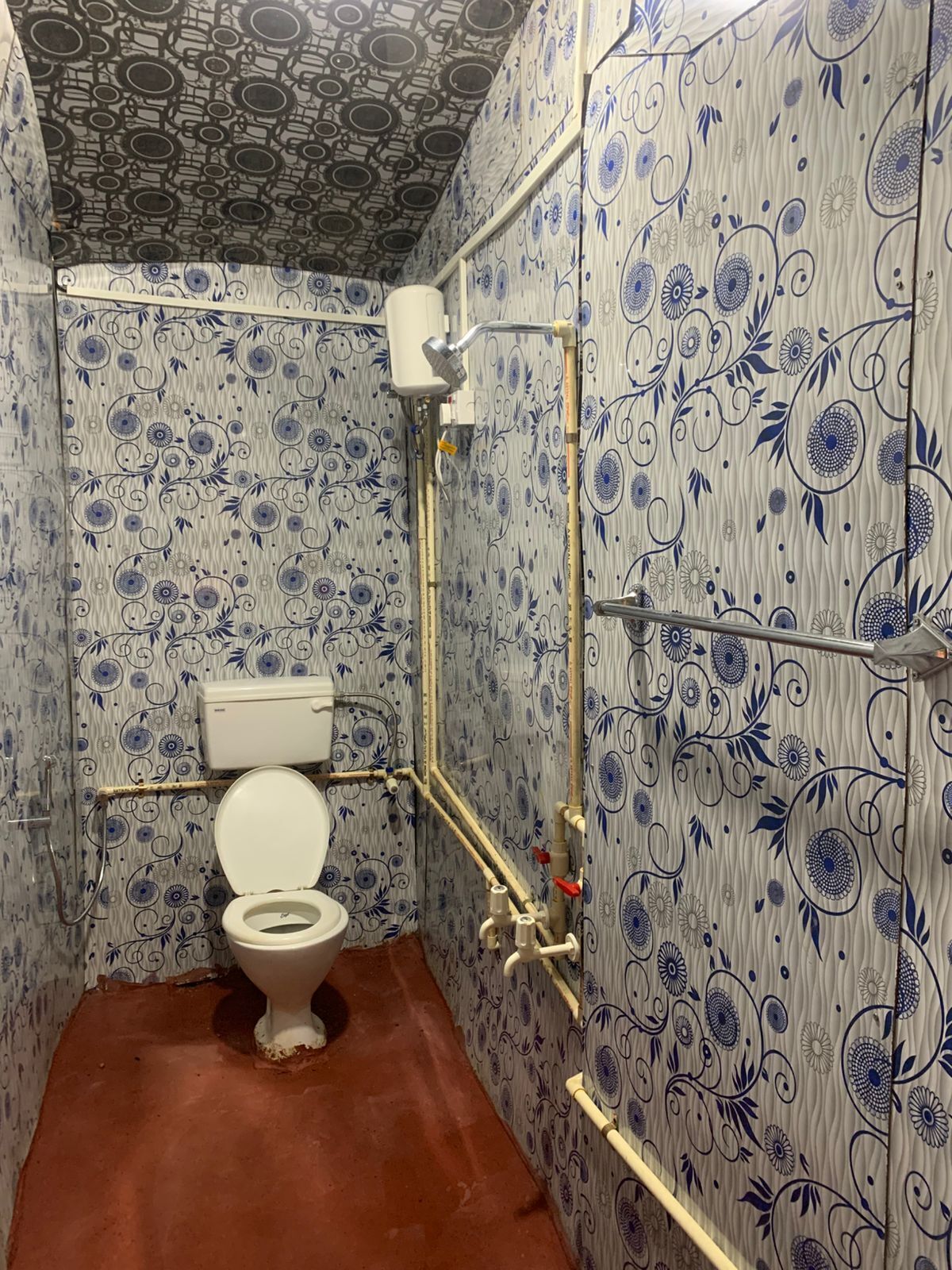 Une salle de bain avec des toilettes, une douche et des murs décorés de motifs.
