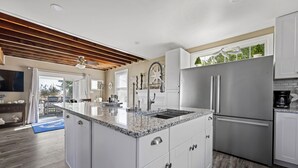 Una cocina moderna con armarios blancos, encimera de granito y electrodomésticos de acero inoxidable.