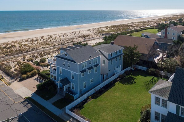 Une grande maison à deux étages, dotée d’un toit plat, située près d’une plage.