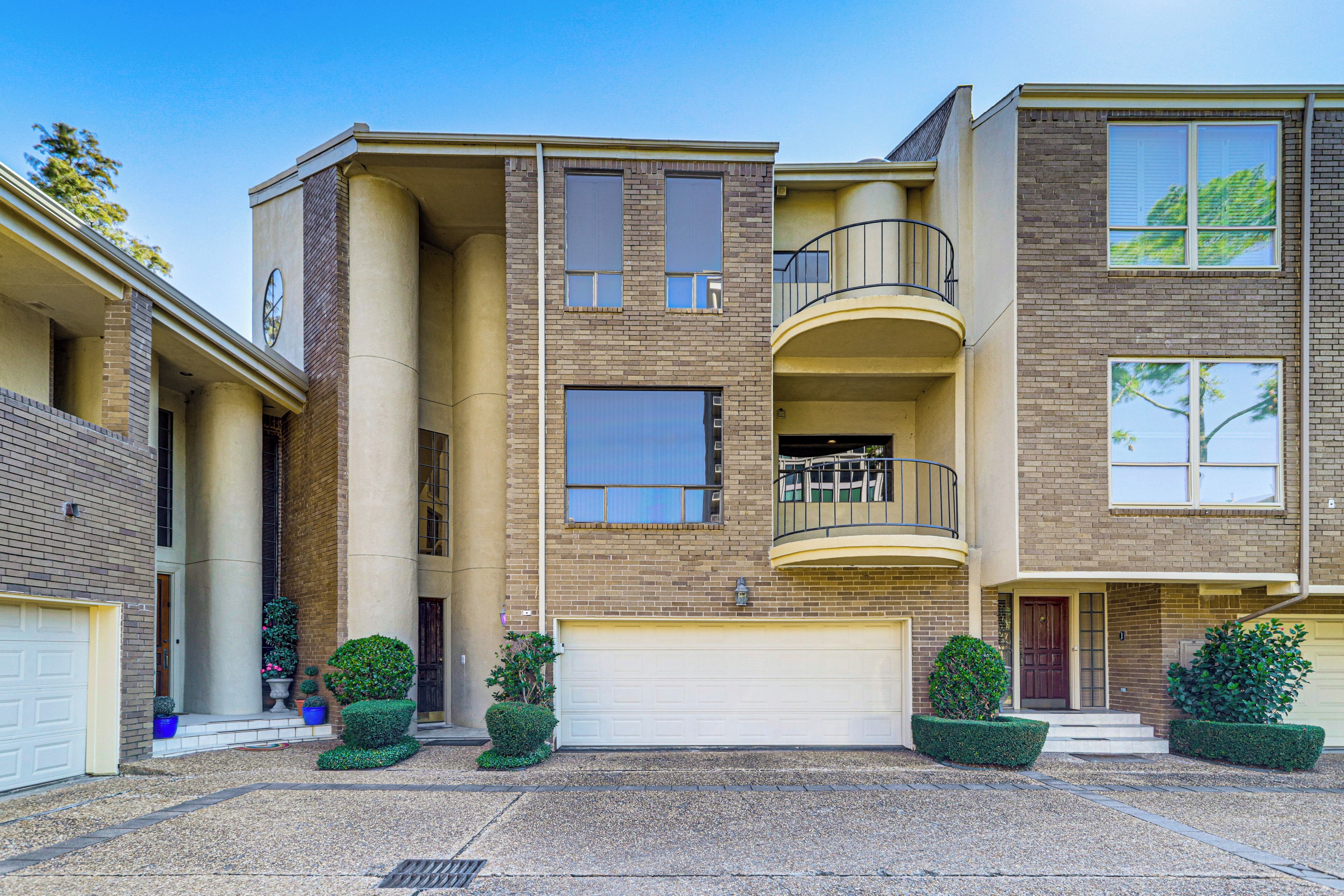 A multi-story residential building with a central courtyard, a garage, and a balcony on the upper floor.