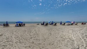 Une plage de sable avec plusieurs chaises de plage et des parasols.