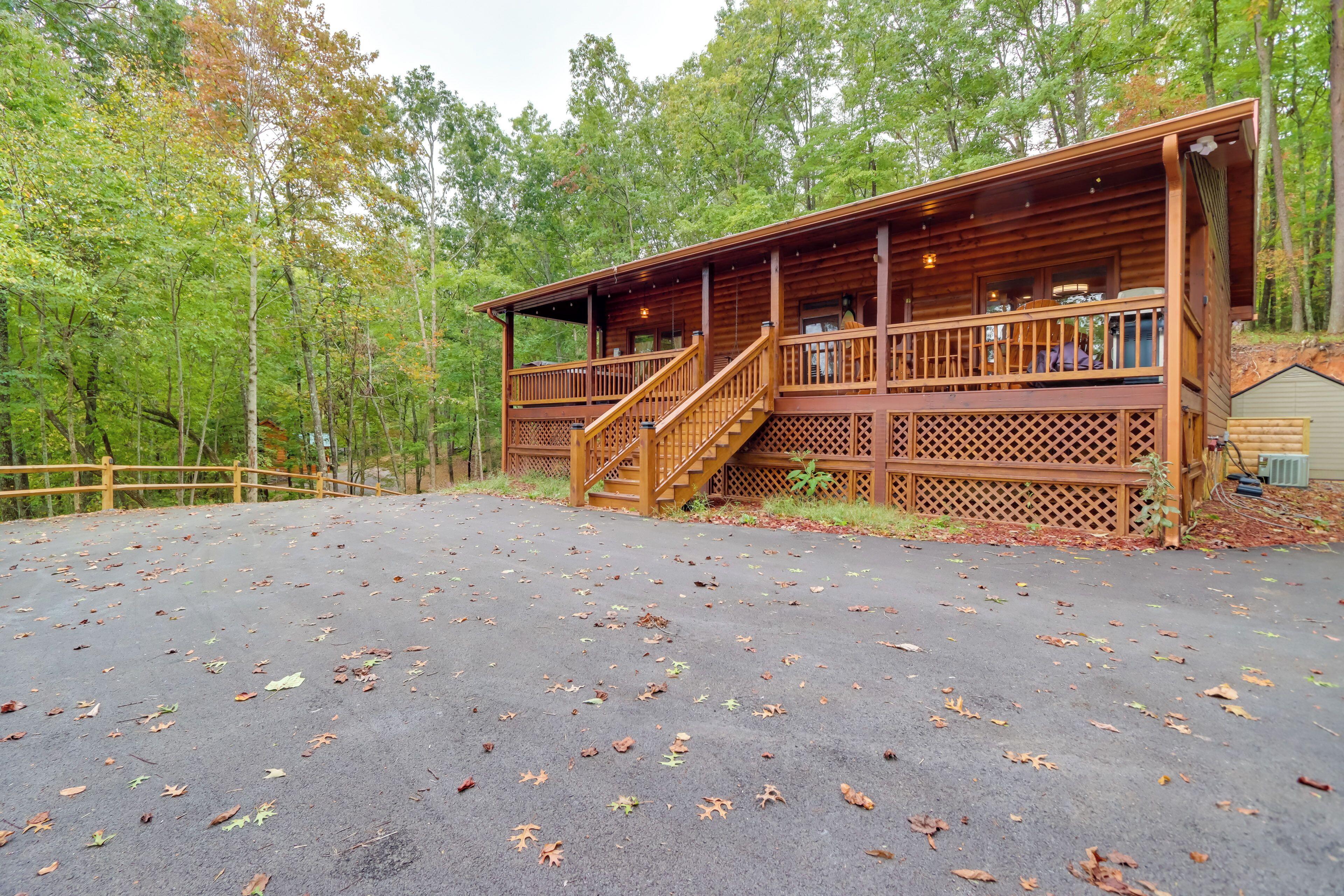 A wooden cabin with a covered deck and stairs leading to a balcony.