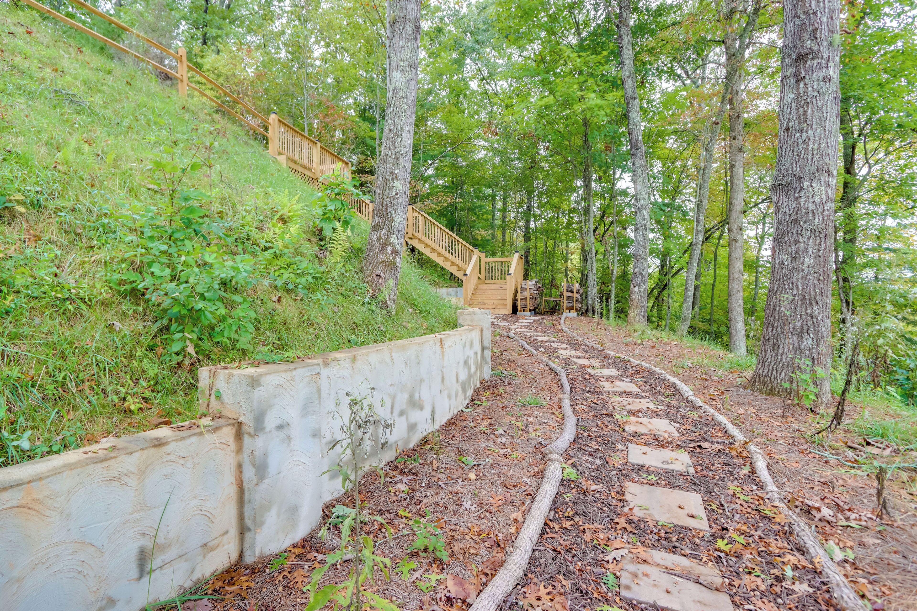 A wooden staircase leading up a grassy slope, surrounded by trees.