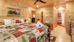 Ein Schlafzimmer in einer Holzhütte mit einem Bett, einem Deckenventilator und einem Bärenbild.