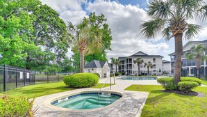 A swimming pool area with a paved deck, surrounded by well-maintained grass and palm trees. - Myrtle Beach Condo w/ Pool Access: 5 Mi to Ocean (Myrtle Beach)
