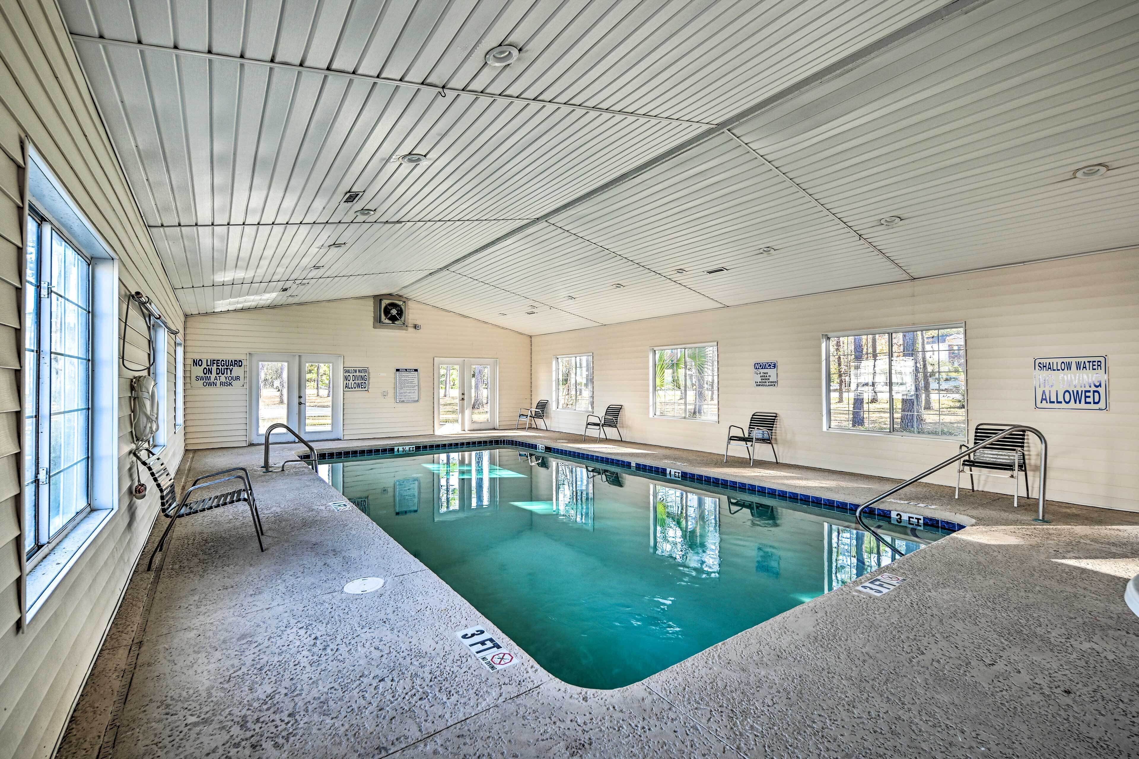 An indoor swimming pool with clear water, a lifeguard station, and signs indicating shallow water is allowed.
