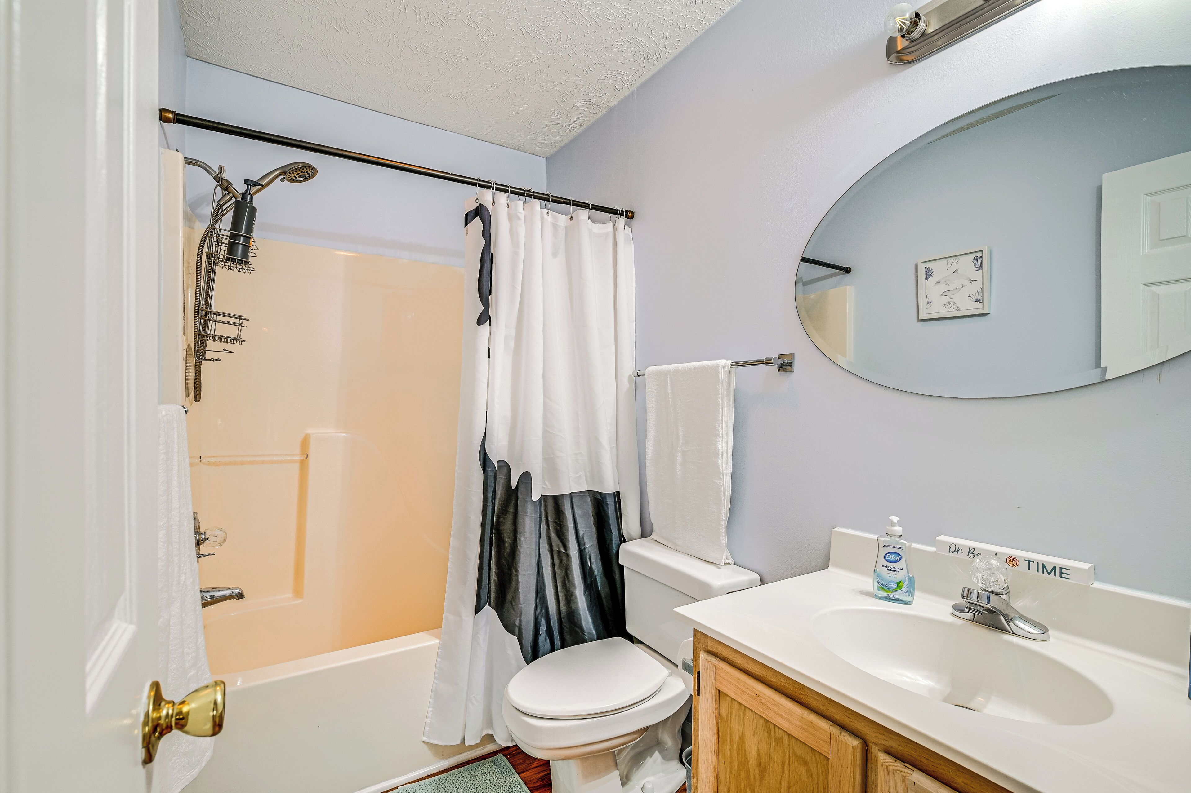 A bathroom with a shower, toilet, sink, and a mirror.