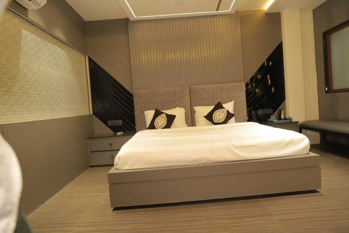 A modern bedroom with a large bed, a nightstand, and a bench.
