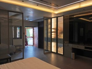 Una habitación de hotel moderna con una cama grande, zona de estar y vistas al exterior.