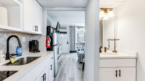 A compact kitchen with white cabinets, a stainless steel sink, and a coffee maker. - 2 Blocks to Beach: Modern Condo in North Wildwood! (North Wildwood)