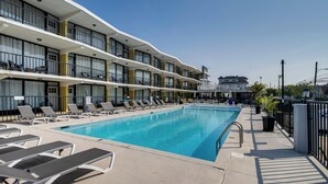 A hotel with a swimming pool, sun loungers, and a multi-story building with balconies. - 2 Blocks to Beach: Modern Condo in North Wildwood! (North Wildwood)