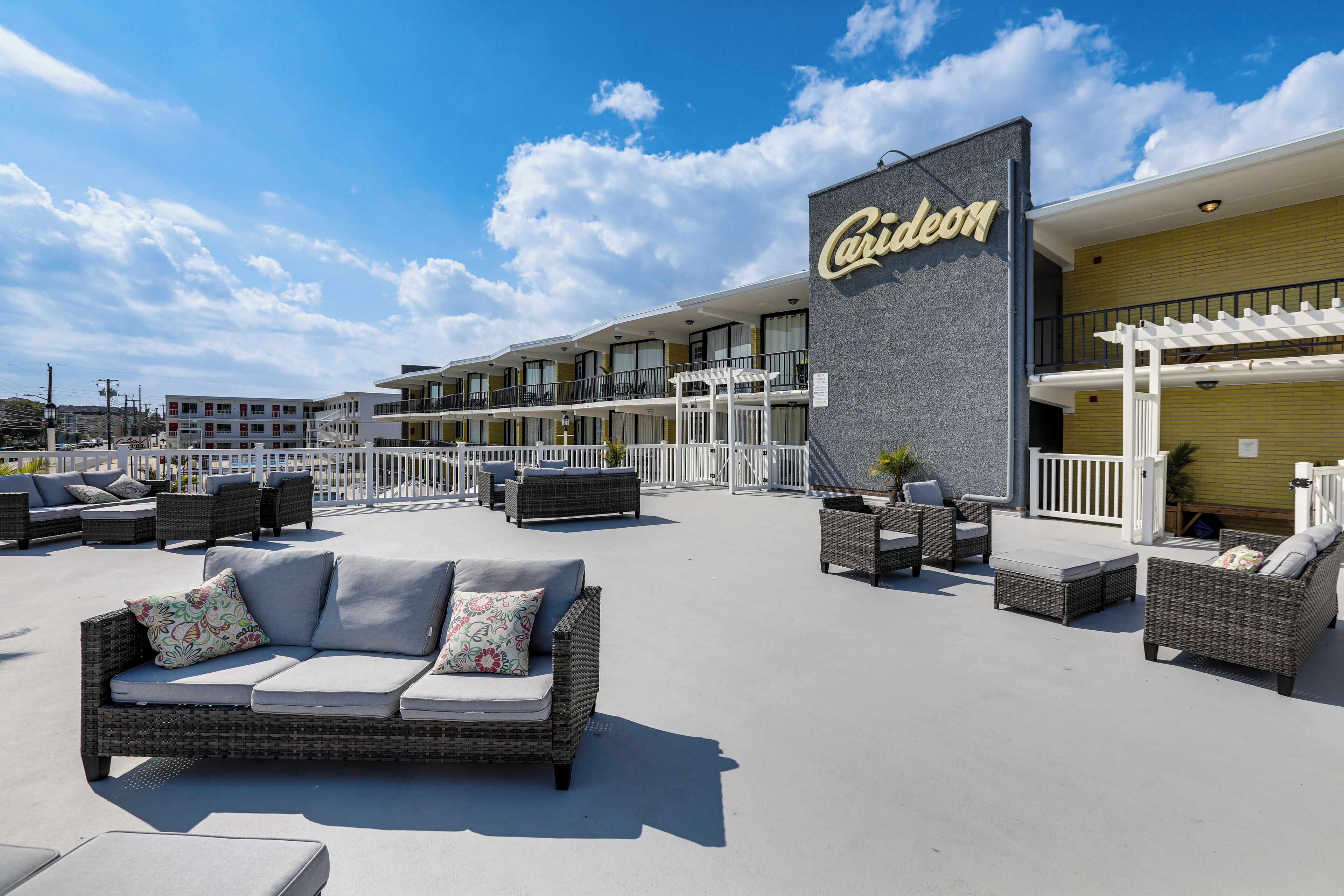 Hotel med udendørs siddeområder, en overdækket terrasse og et skilt med teksten "Caireon".