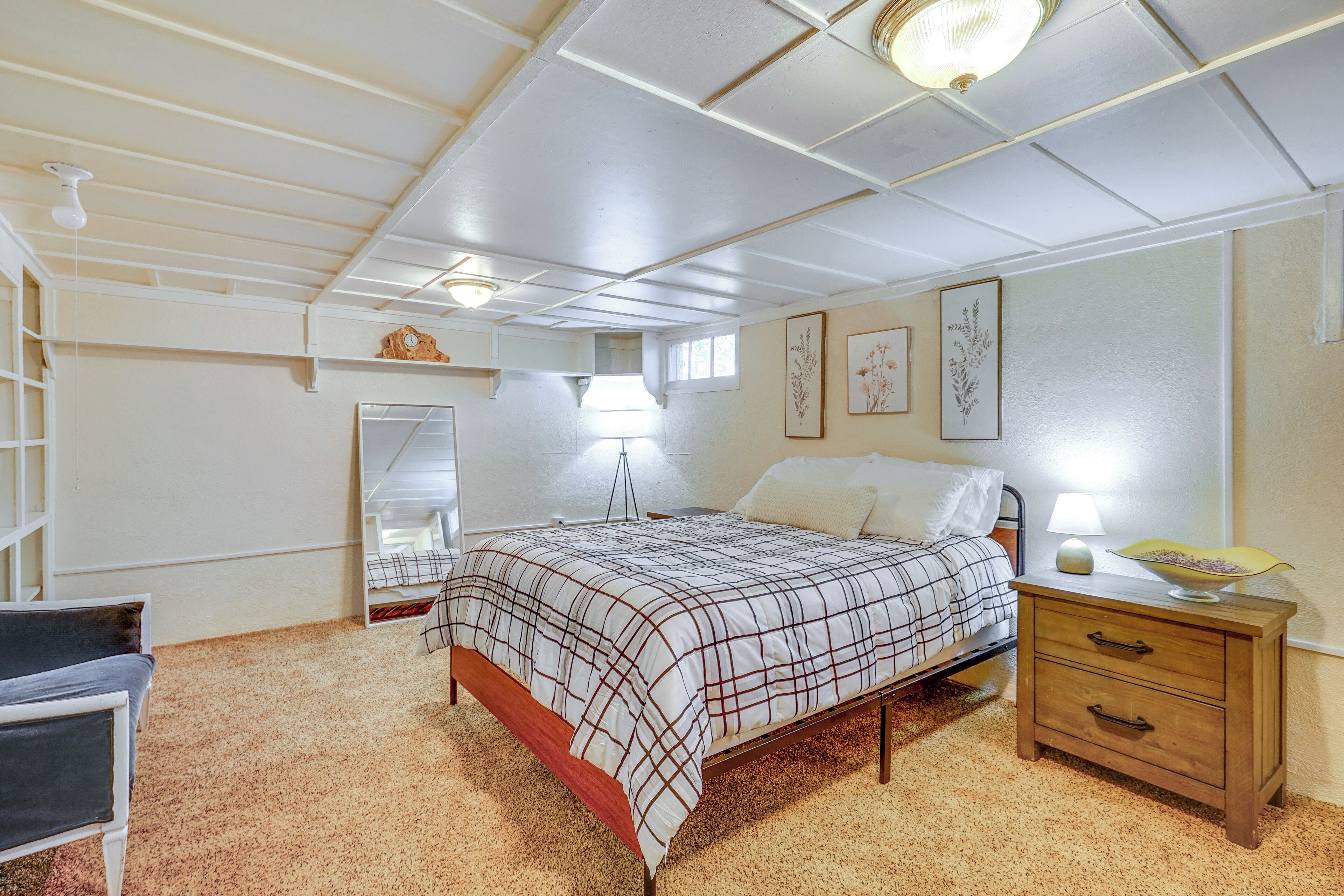 Un dormitorio con cama, mesita de noche, lámpara y espejo.