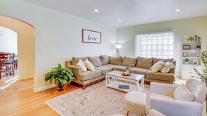 Un salón con un sofá beige, una mesa de centro blanca y un sillón blanco.