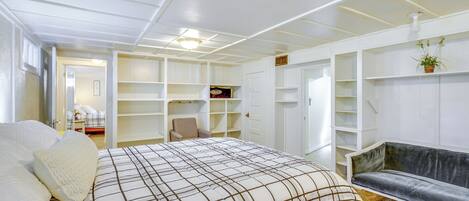 A bedroom with a large bed, a sofa, and built-in shelving.