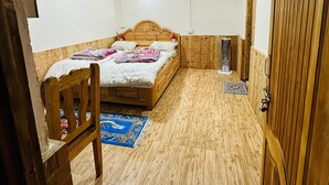 A wooden-paneled room with a bed, a chair, and a door. - Vansh Green View Homestay (Sainj)