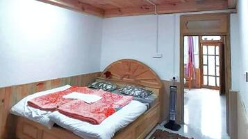 A bedroom with a wooden ceiling, a bed with a red and white bedspread, and a patterned rug on the floor.