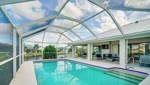 Une piscine couverte à l’eau d’un bleu cristallin, entourée d’une structure blanche aux panneaux de verre.