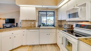 Une cuisine moderne avec des armoires blanches, un plan de travail en granit, un four à micro-ondes encastré et un four traditionnel.