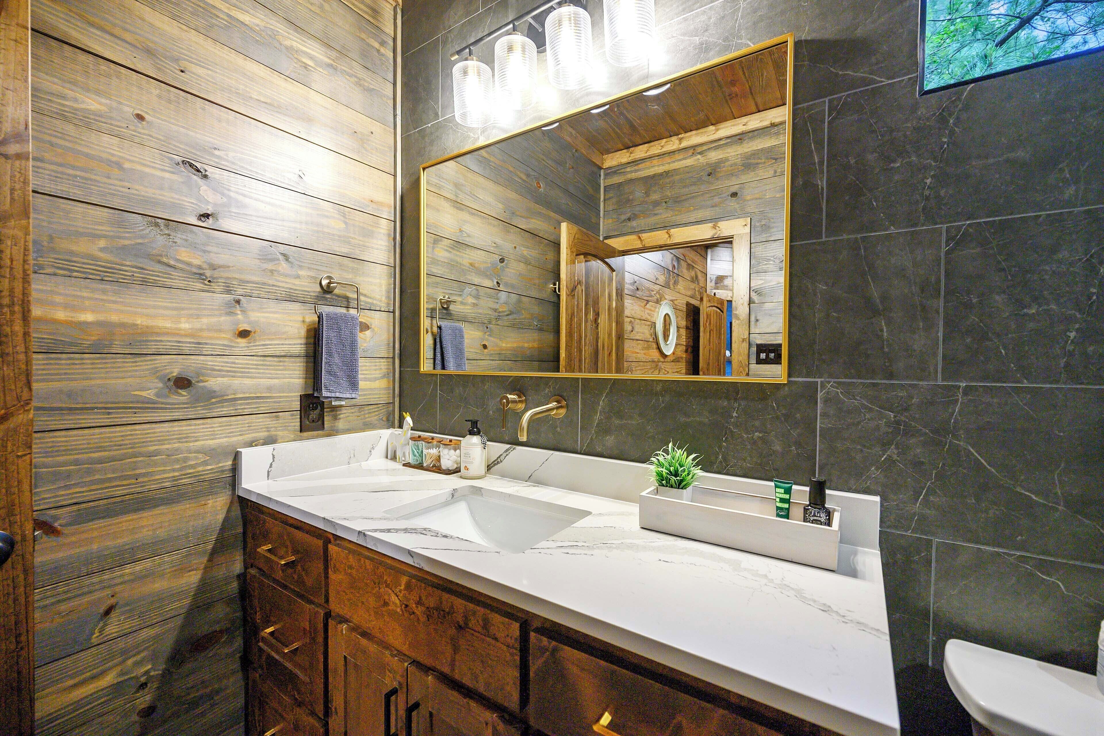 Een badkamer met houten wanden, een grote spiegel, twee wastafels en een toilet.