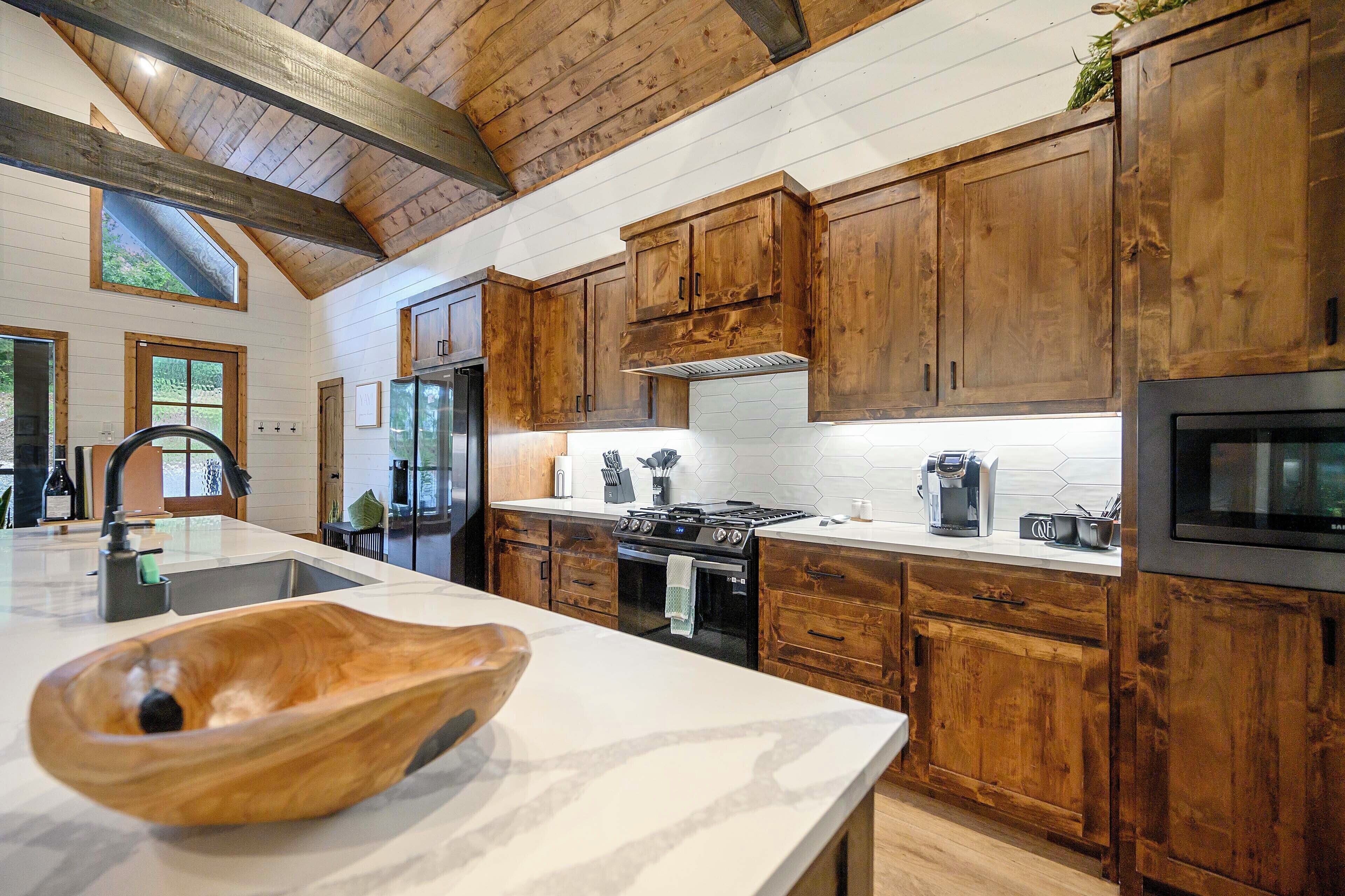 A kitchen with wooden cabinets, a large island with a bowl, a stove, and a microwave.