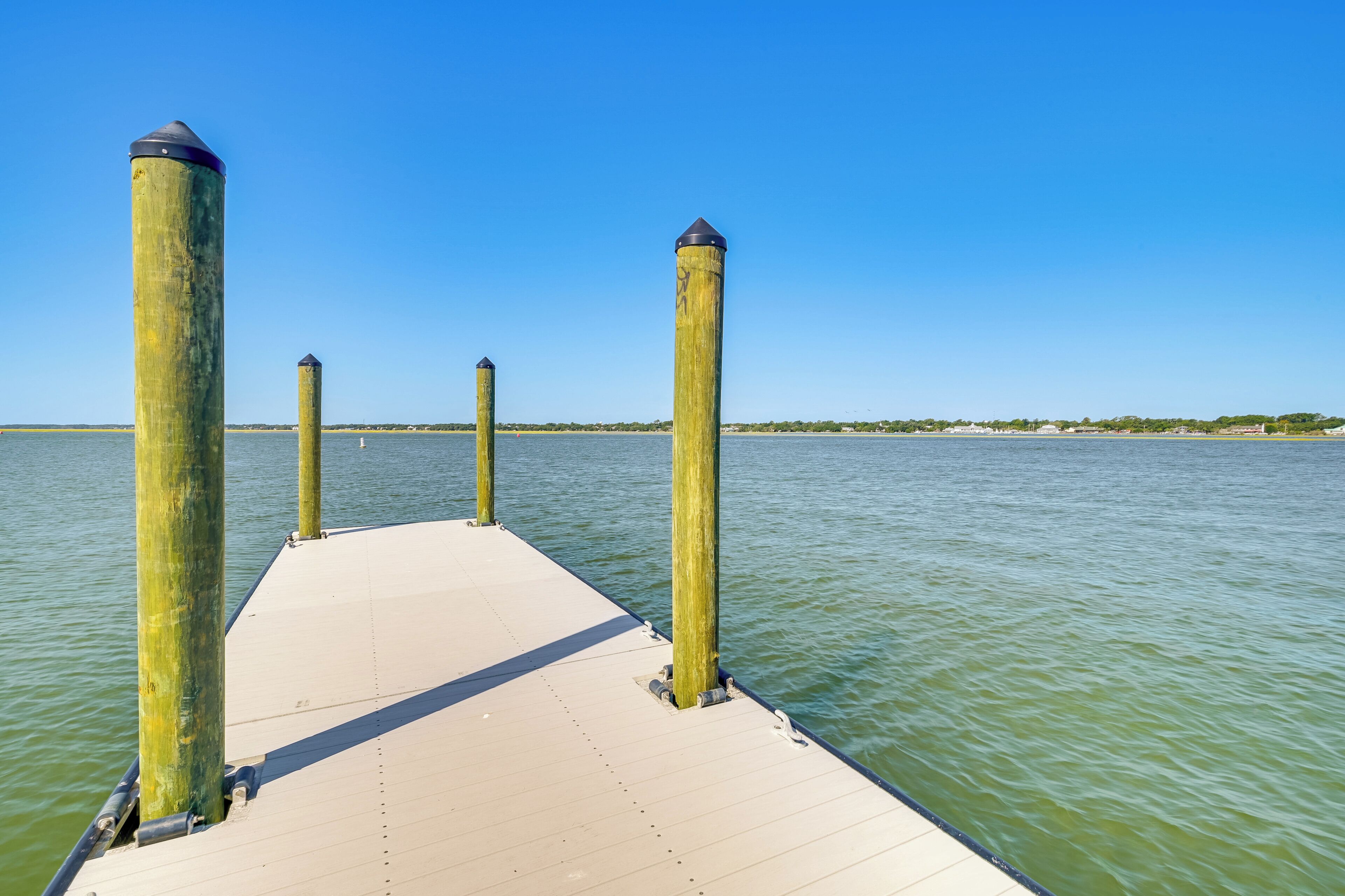 A wooden pier extending into calm water with a clear sky.