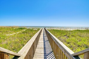 A wooden boardwalk leading to a beach with grassy dunes and a clear blue sky. - Private Beach & Pool Access: Murrells Inlet Condo! (Murrells Inlet)