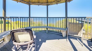 A covered deck with a wooden bench and a chair, overlooking a body of water and grassy area. - Private Beach & Pool Access: Murrells Inlet Condo! (Murrells Inlet)