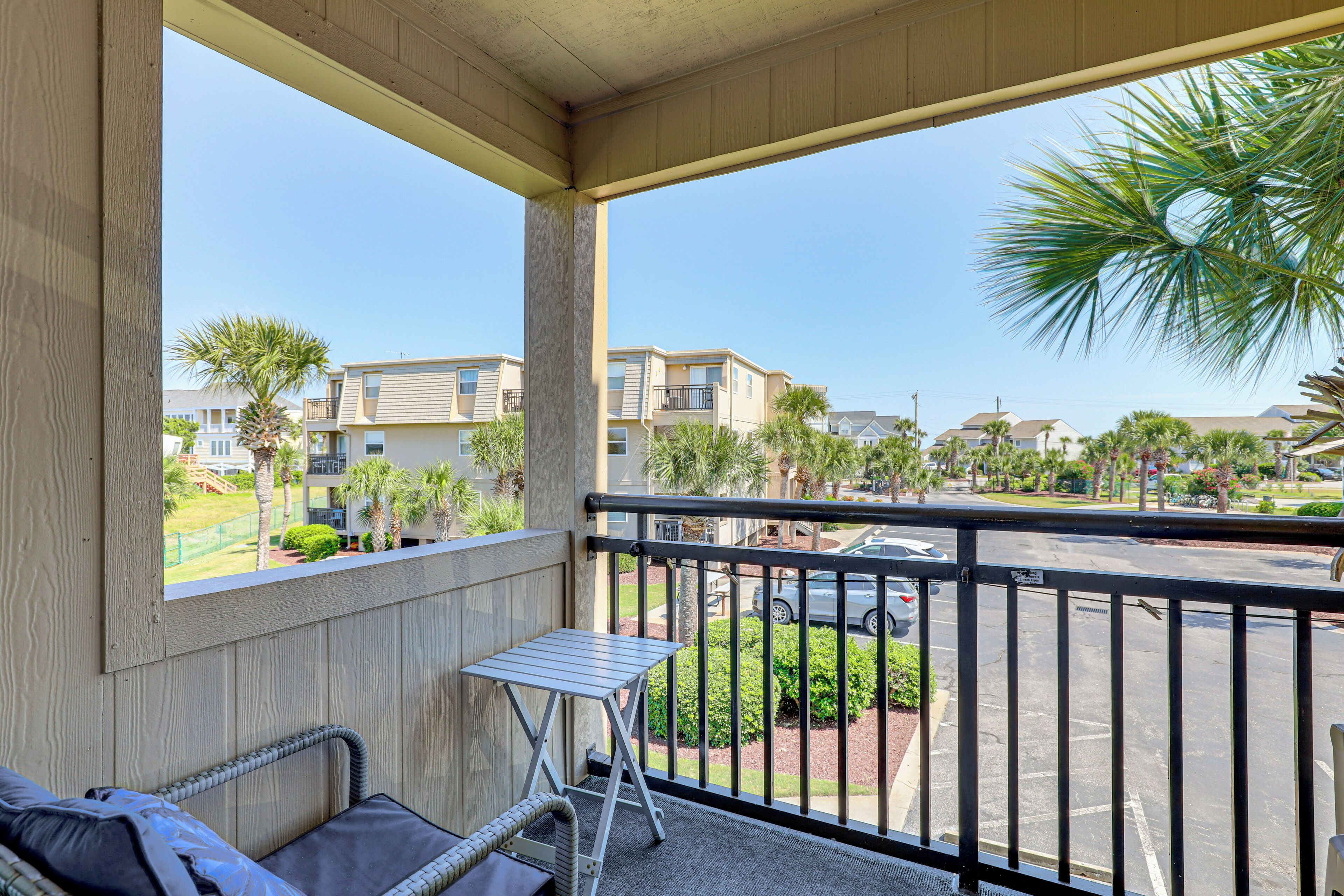 A balcony with a view of a residential area, including buildings and palm trees.
