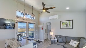 A modern kitchen with a large island, a dining area with a view, and a living room with a gray sofa and a framed picture on the wall. - "the Farmhouse": Near Flathead Lake & Skiing (Kalispell)