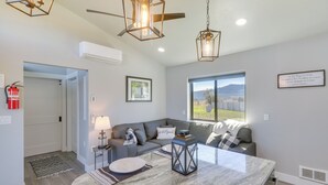 A modern living room with a marble island, a grey sofa, and a large window with a view. - "the Farmhouse": Near Flathead Lake & Skiing (Kalispell)