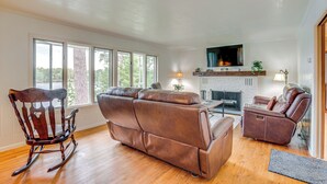 Ein geräumiges Wohnzimmer mit Kamin, Ledersofas und einem Schaukelstuhl.