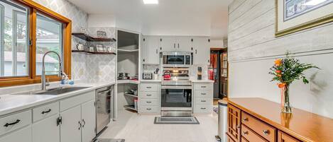 A modern kitchen with white cabinetry, a wooden countertop, and a built-in oven.
