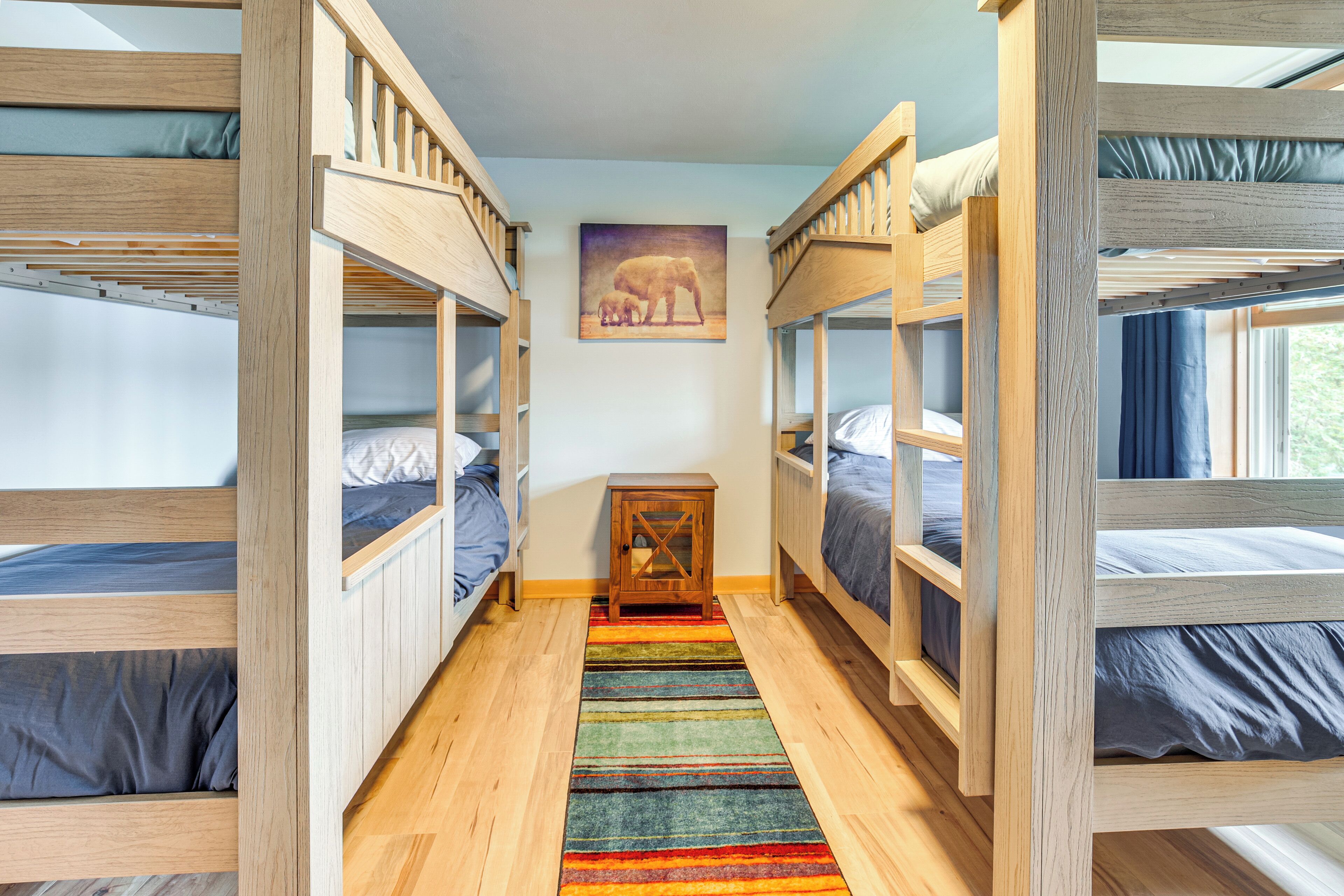 A room with bunk beds, a colorful striped rug, and a painting of an elephant on the wall.