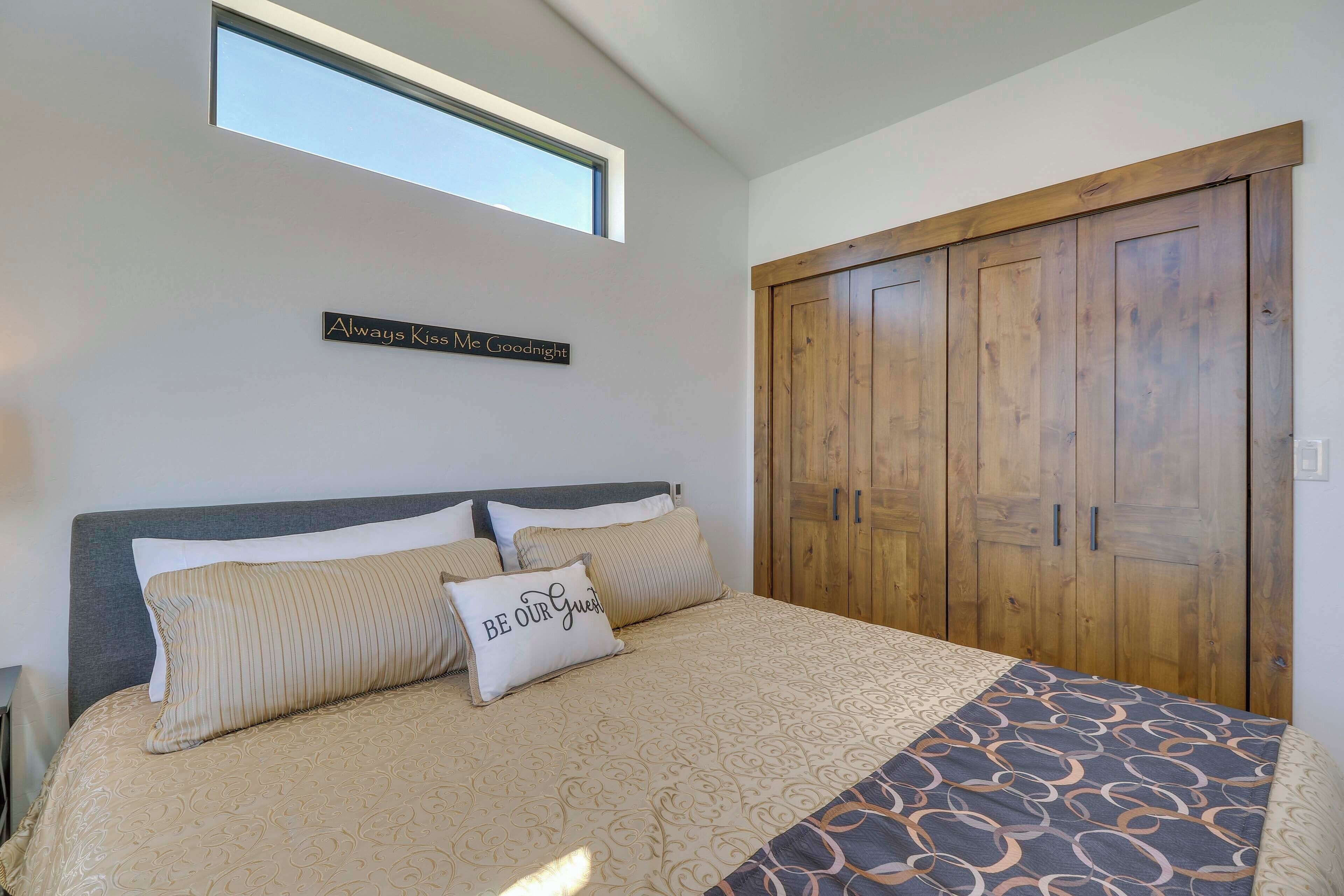 A bedroom with a large bed, a skylight, a wooden wardrobe, and a sign on the wall.