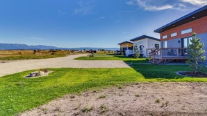 A modern building with a gravel driveway, grassy areas, and a clear sky. - "montana Blue" w/ Grill Near Skiing! (Kalispell)