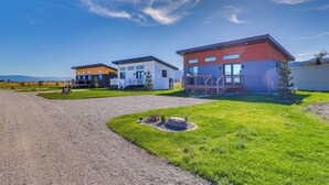 A modern residential area with two houses, a gravel driveway, and a well-maintained lawn. - "montana Blue" w/ Grill Near Skiing! (Kalispell)