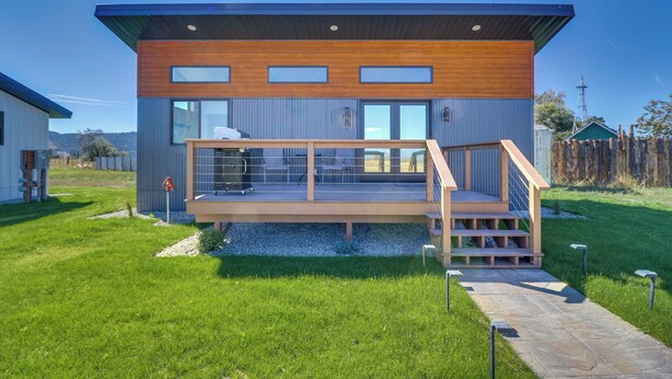 A modern two-story house with a wooden deck and a small staircase leading to the upper level. - "montana Blue" w/ Grill Near Skiing! (Kalispell)