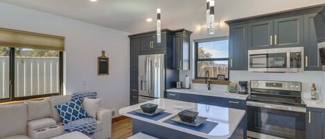 A modern kitchen with dark cabinets, stainless steel appliances, and a central island with stools.