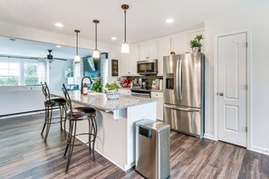 A modern kitchen with stainless steel appliances, a central island with bar stools, pendant lighting, and a view of the outdoors. - 2 Mi to Hollywood Casino: Charles Town Townhome! (Charles Town)